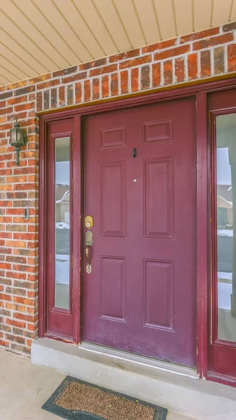 Vertical Facade of a home with a red front door and reflective sidelights and windows