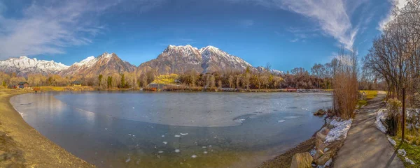 Panorama claro Panorama panorâmico de um lago contra a montanha coberta de neve e o céu azul no inverno — Fotografia de Stock