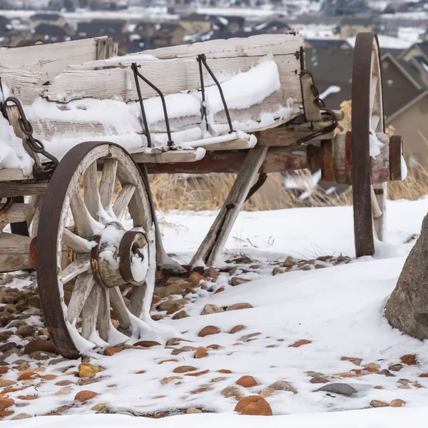 Heldere vierkante oude houten wagon met kettingen en roestige wielen bestrooit met sneeuw in de winter — Stockfoto