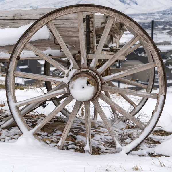 Clear Square Rusty wheel of a wooden cart against a rocky ground covered with snow in winter