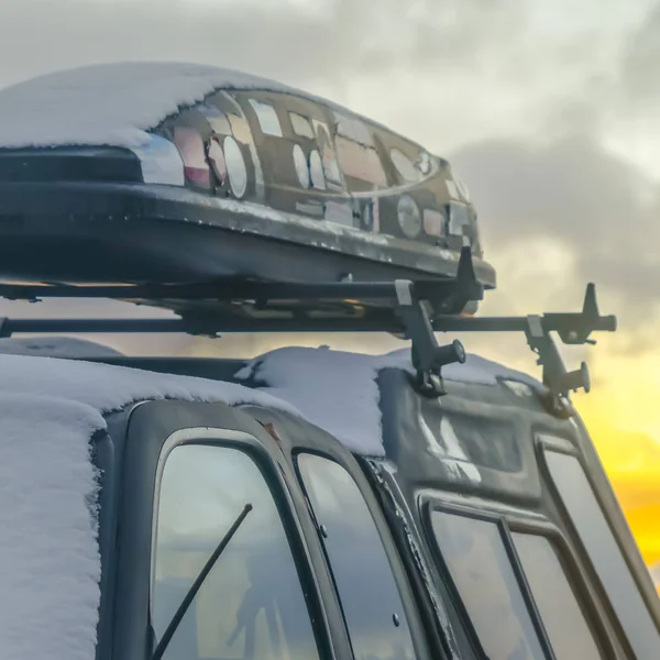 Square Black vehicle with roof rack and car top carrier covered with snow in winter — Stock Photo, Image