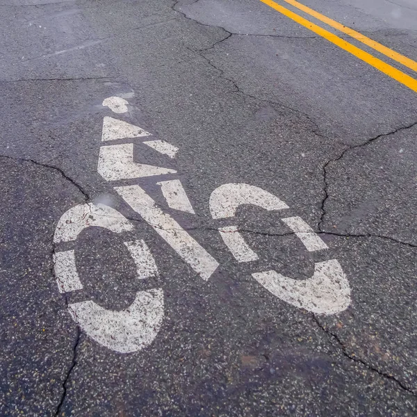Square Bicycle lane symbol painted on a damaged road