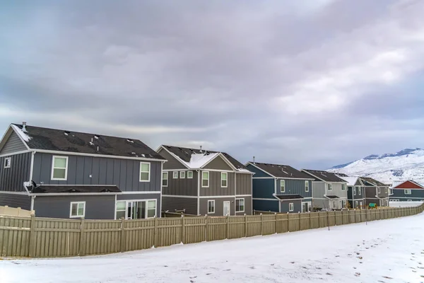 Casas encantadoras com neve tampada montanha e céu cheio de nuvens no fundo — Fotografia de Stock