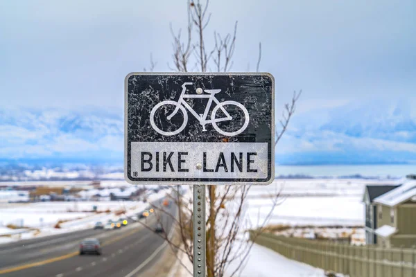 Bike Lane sign post in front of a tree and snow covered landscape in winter