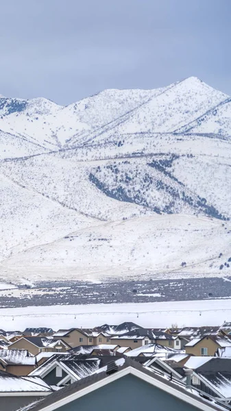 Techos nevados verticales claros de las casas con una vista impresionante de la montaña cubierta de nieve en invierno —  Fotos de Stock