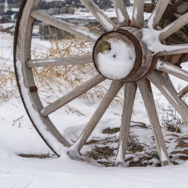 Square Close up of the wooden wheel of an old wagon against a snowy terrain in winter