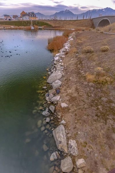 Lac avec des rochers bordant le rivage et un pont voûté au-dessus de ses eaux brillantes — Photo