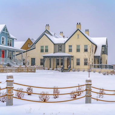 Kışın karla kaplı zemin üzerinde bir ip çit ötesinde Square Adorable evleri