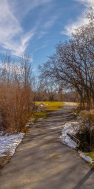 Kışın karla kaplı dağ ve mavi gökyüzüne karşı bir gölün Dikey Manzara panoraması