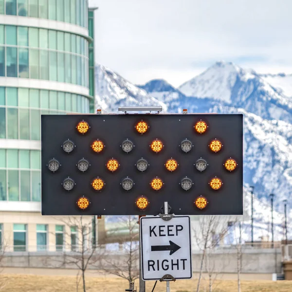 Klares Quadrat rechts unter einer Pfeiltafel halten, die von Verkehrssicherheitsmasten umgeben ist — Stockfoto