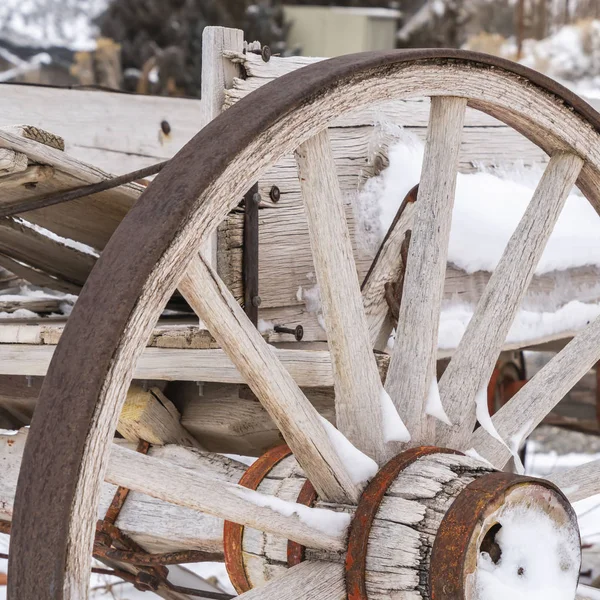 Square Close up of the wheel of an old wooden cart against a snowy landscape in winter