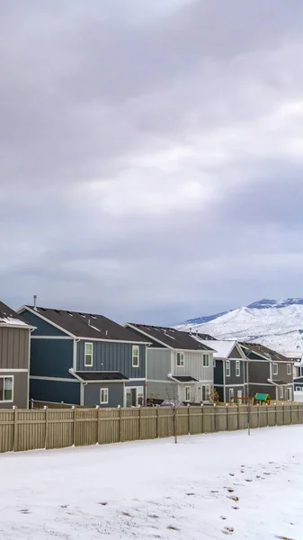 As casas encantadoras verticais com neve tampou a montanha e o céu enchido nuvem no fundo — Fotografia de Stock