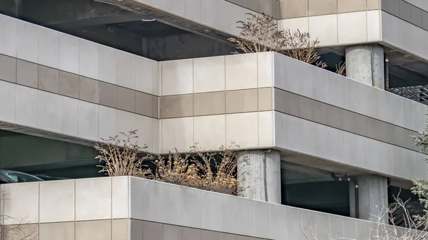 Blick von außen auf den überdachten Parkplatz eines Gebäudes mit Fahrzeugen und Pflanzen — Stockfoto