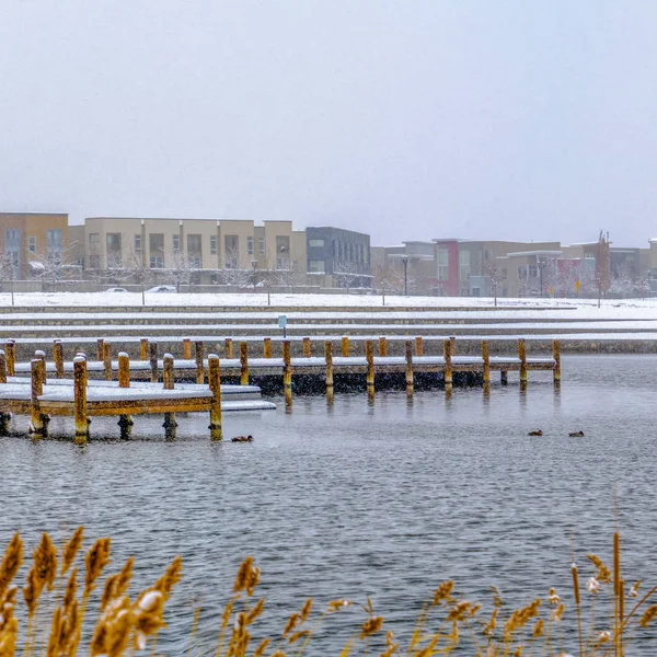 Edificios cuadrados contra el cielo en un paisaje cubierto de nieve más allá del lago en invierno — Foto de Stock