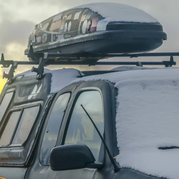 Vierkante sneeuw bedekt zwart voertuig met een Car top Carrier gemonteerd op de dakdrager — Stockfoto