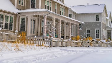 Daybreak bulutlu bir gökyüzü altında rahat evler ve ahşap çitler ile Panorama Kış sahnesi