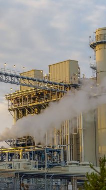 Dikey Güç Santrali parlak kabarık bulutlar ile soluk mavi gökyüzüne karşı buhar serbest