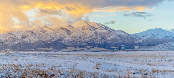 Montagne majestueuse au-delà du terrain herbeux recouvert de neige en hiver — Photo