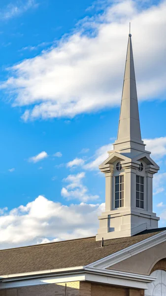 Exterior vertical claro de una hermosa iglesia con un campanario blanco contra el cielo azul nublado — Foto de Stock