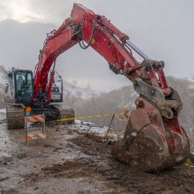 Barikatlar ve kışın izlenen sarı bant ile çamurlu bir yolda Clear Square Ekskavatör