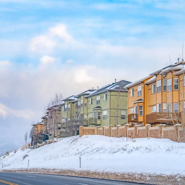 Quadrado Vista panorâmica de casas coloridas em uma encosta nevada ao lado de uma estrada pavimentada no inverno — Fotografia de Stock