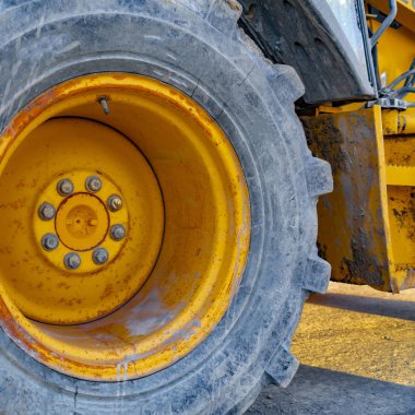 Kare Güneşli bir günde yolda park edilmiş sarı bir yükleyicinin tekerleğinin kapatılması