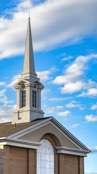 Vertical Exterior of a beautiful church with a white steeple against cloudy blue sky — Stock Photo, Image
