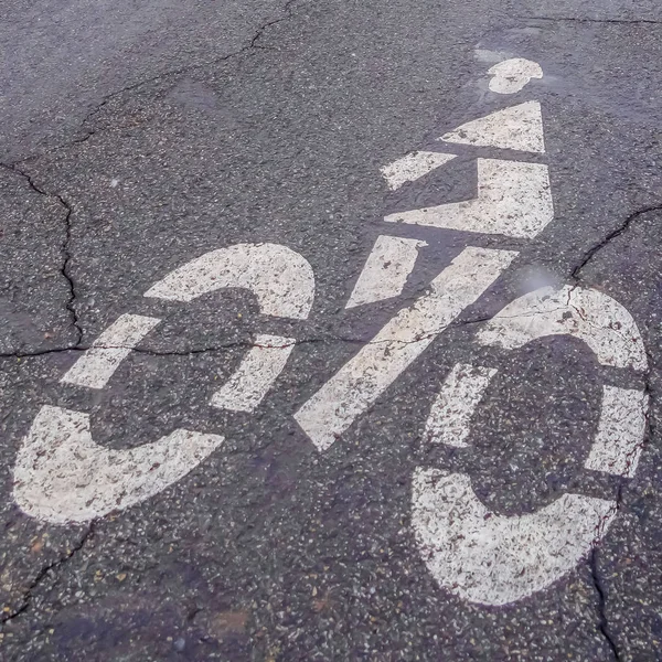 Square Bicycle lane sign painted on a road with cracks