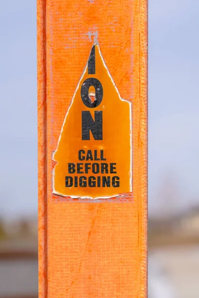 A torn Caution sign on a bright orange post against a blurry background