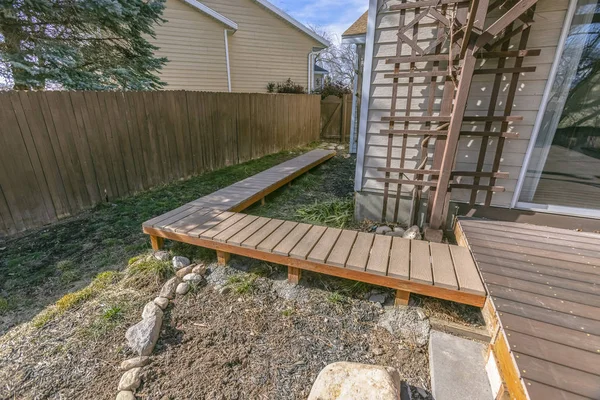 Wooden walkway inside the yard of a home viewed on a sunny day
