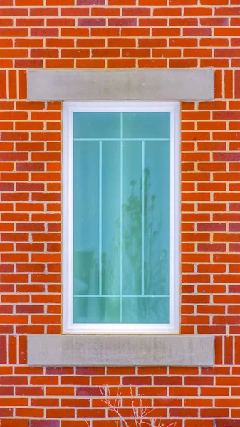 Clear Vertical Close up of the rectangular window of a building with red brick wall
