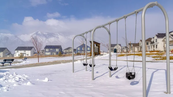 Clear Panorama Baby swings at a playground blanketed with clean snow on a sunny winter day