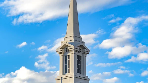 Panorama claro Exterior de una hermosa iglesia con un campanario blanco contra el cielo azul nublado — Foto de Stock