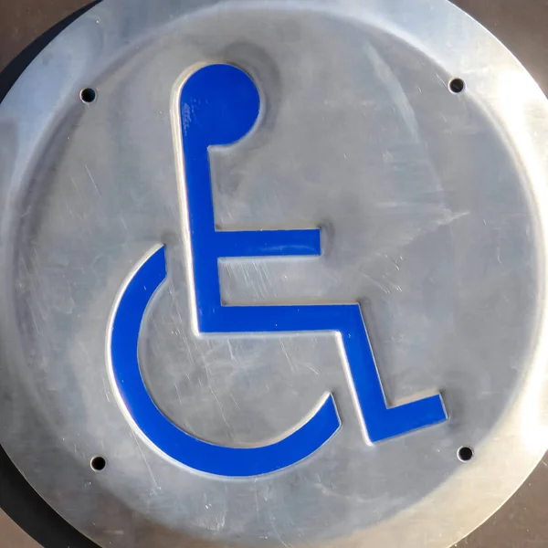 Clear Square Close up of a Disabled Sign engraved on a circular metal viewed on a sunny day — Stock Photo, Image