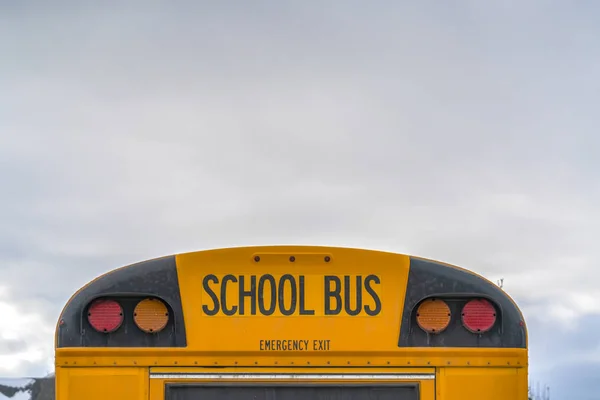 Rear of a yellow school bus with signal lights and emergency exit window