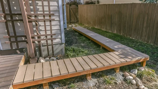 Panorama Wooden walkway inside the yard of a home viewed on a sunny day