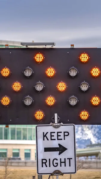 Vertical Close up of an arrow board and Keep Right sign against a modern building — Stock Photo, Image