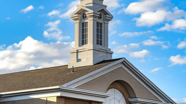 Panorama Exterior de una hermosa iglesia con un campanario blanco contra el cielo azul nublado — Foto de Stock