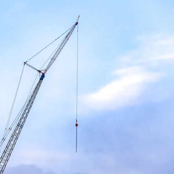 Clear Square A lifting crane viewed against a beautiful blue sky filled with cottony clouds — Stock Photo, Image