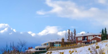 Kabarık bulutlar ile gökyüzüne karşı karlı tepede Homes