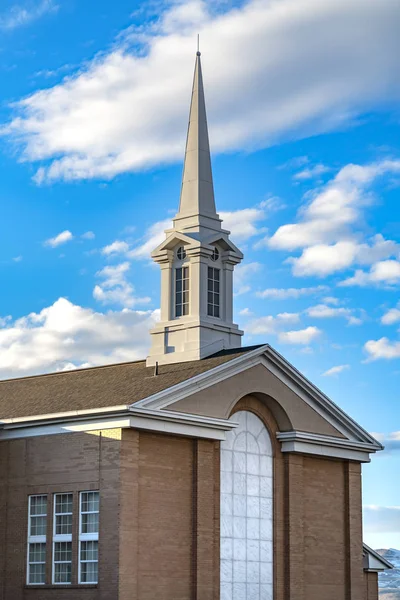 Exterior de una hermosa iglesia con un campanario blanco contra el cielo azul nublado — Foto de Stock