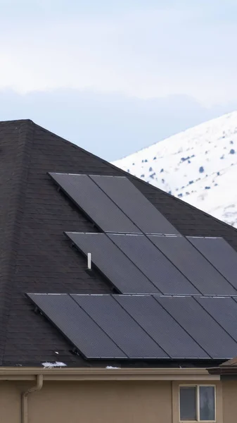 Чистые вертикальные солнечные панели, установленные на темной крыше дома с снегом зимой — стоковое фото