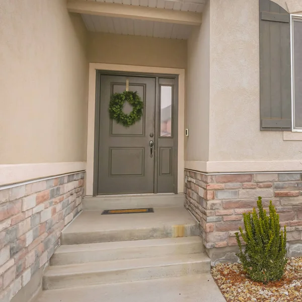 Clear Square Pathway and stairs leading to the gray front door with wreath and sidelight