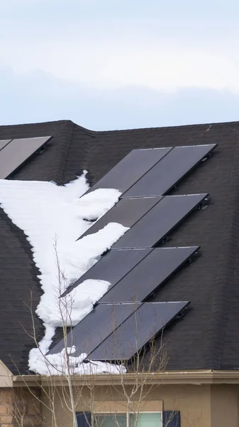 Painéis solares verticais instalados no telhado escuro de uma casa com neve no inverno — Fotografia de Stock