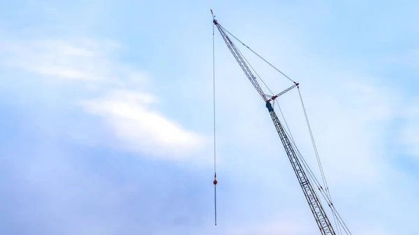 Panorama A lifting crane viewed against a beautiful blue sky filled with cottony clouds — Stock Photo, Image