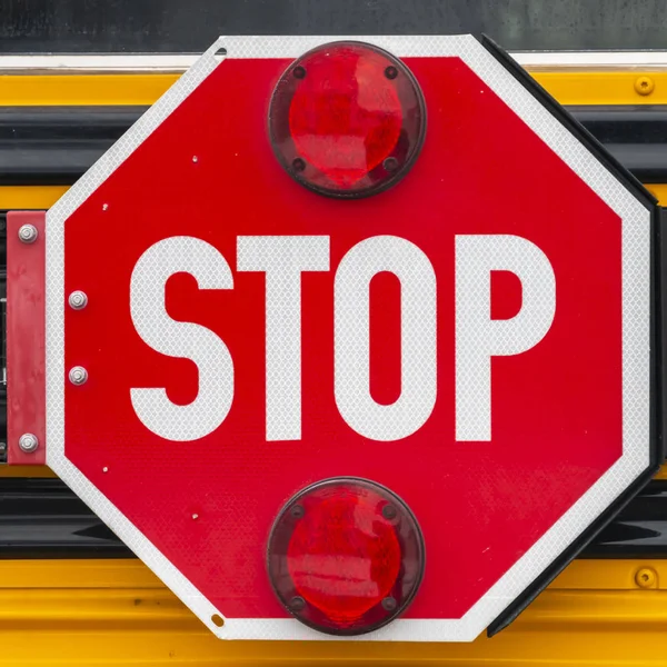 Klare quadratische Nahaufnahme eines achteckigen roten Stoppschildes mit Signalleuchten an einem Schulbus — Stockfoto