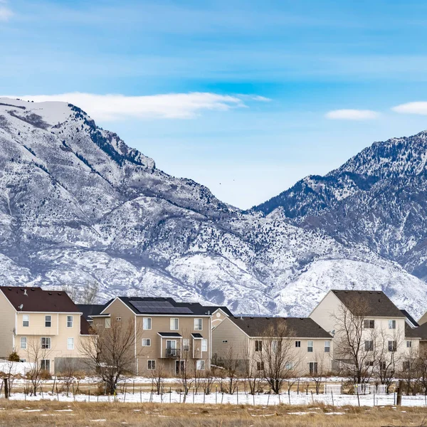 Borrar Plaza Fila de hermosas casas contra una escarpada montaña espolvoreada con nieve en invierno — Foto de Stock