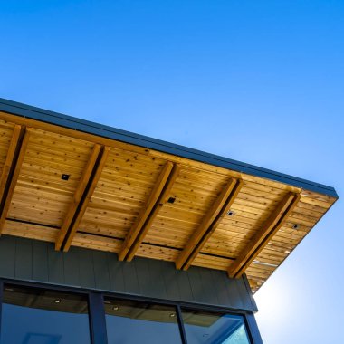 Güneşli bir günde berrak mavi gökyüzü altında düz çatı ve kırmızı tuğla duvar ile Kare Bina