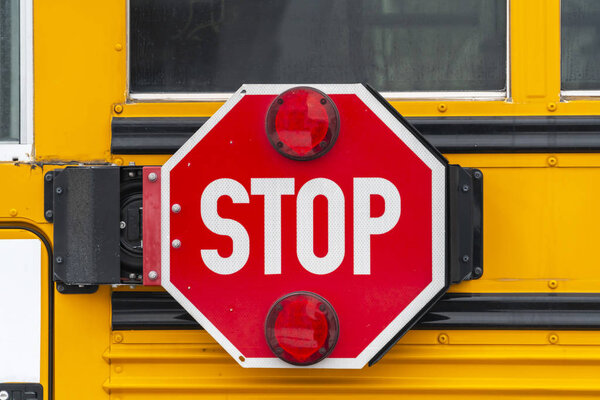 Крупный план красного знака в форме восьмиугольника с сигнальными огнями в школьном автобусе
