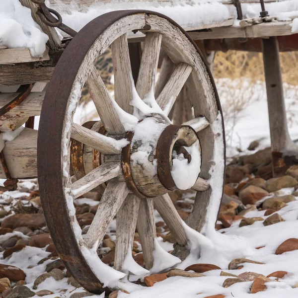 Square An old wooden wagon with rusty wheels dusted with snow in winter